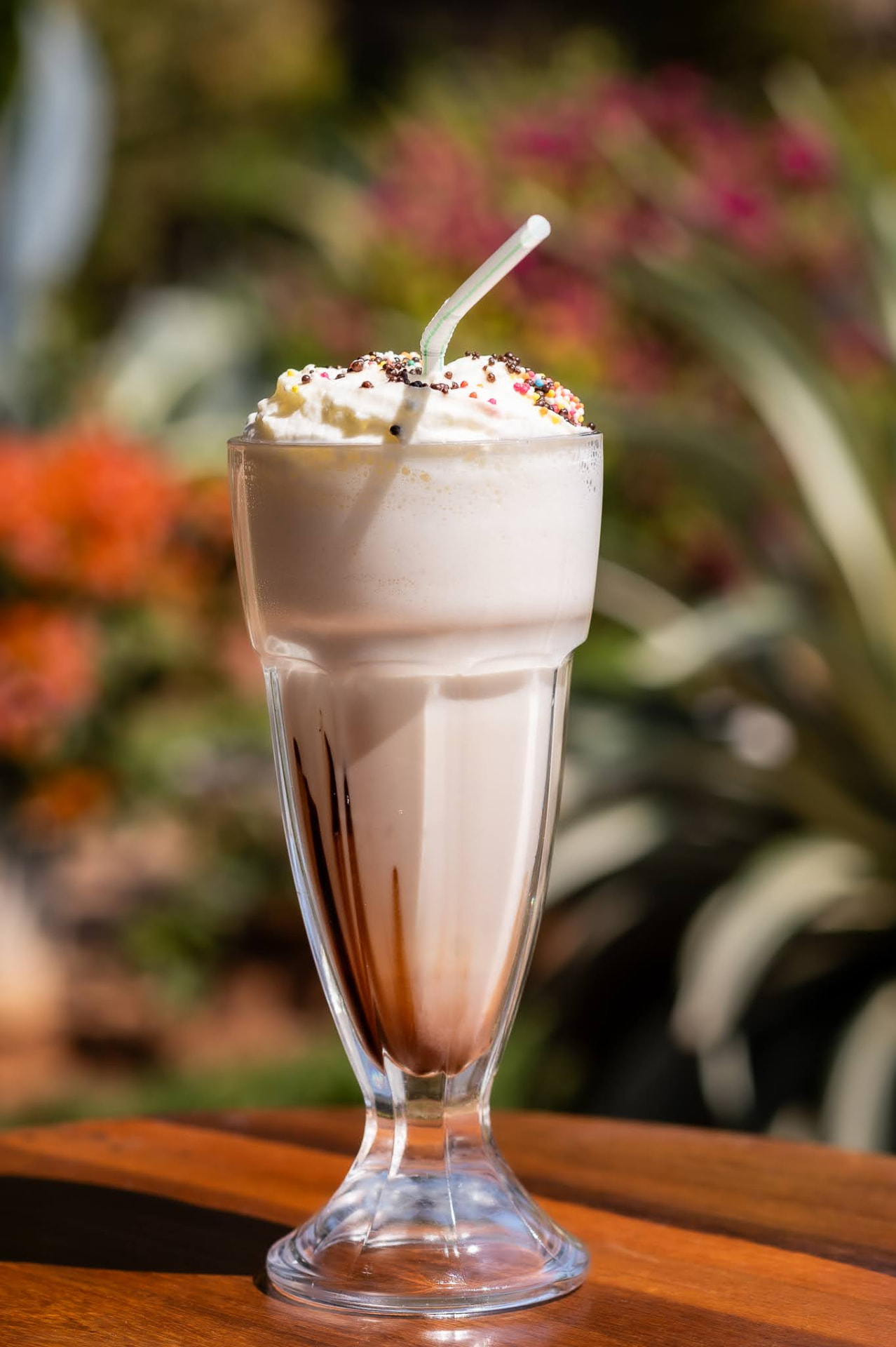 Chocolate milkshake topped with cream and sprinkles in the garden