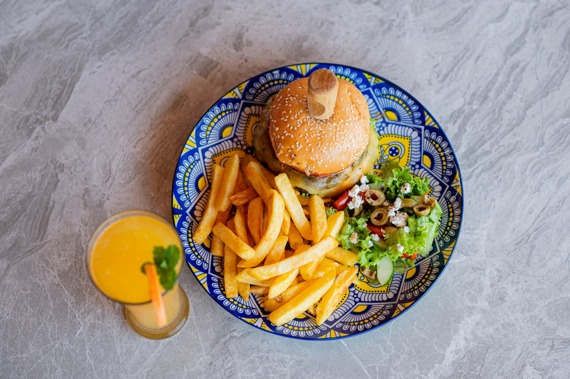 Burger and chips beside a glass of freshly pressed mango juice